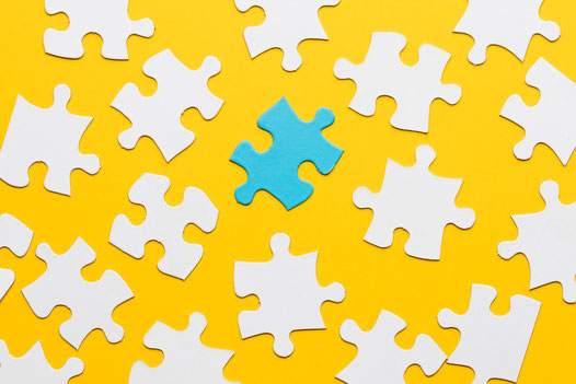 Puzzle with a central blue piece, symbolizing the development of cognitive skills and problem-solving abilities through Spanish courses