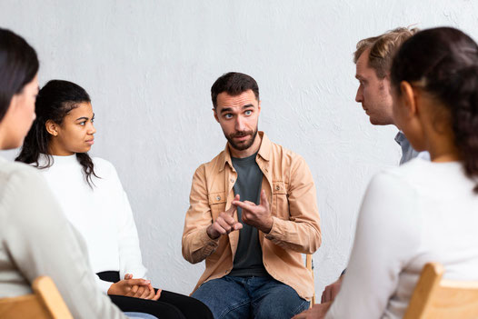 Group of people in a circle discussing a topic during Spanish conversation classes.