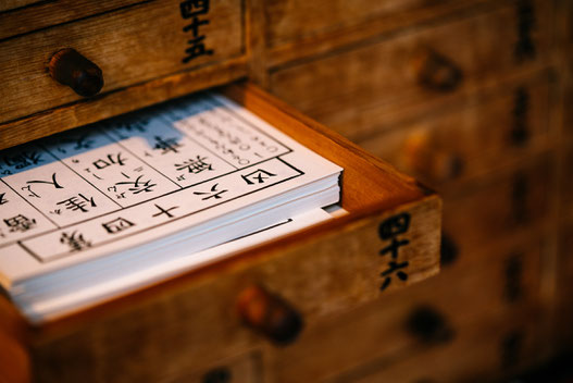 Kleine geöffnete Kommode mit Karten mit chinesischen Schriftzeichen.