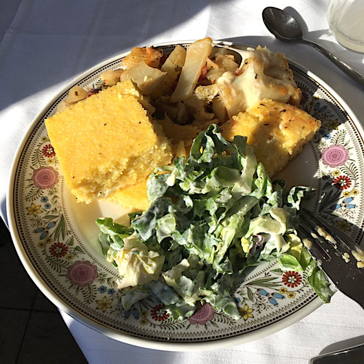 Auf einem Teller mit Blumenmuster ist ein veganes Mittagessen arrangiert.