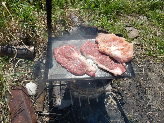 焚き火で肉を豪快に焼いています。