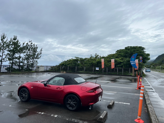 えんじ色のマツダのロードスターが室戸の海の近くの駐車場に停車しています