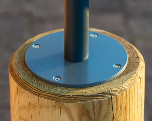 Graue runde Bodenhalterung mit aufgeschraubtem Aluminiumrohr wurde mit vier Schrauben auf einem runden Holzpfosten befestigt