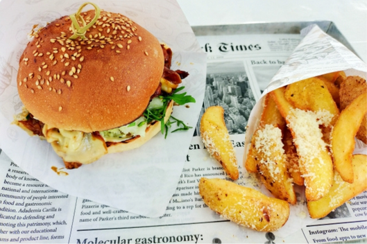 英字新聞が敷かれたトレイにハンバーガーとポテトフライ。