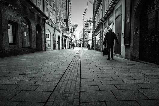 2 men are walking in the otherwise deserted Getreidegasse