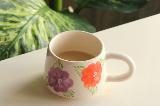 麻のクロスの上に広げられたコーヒー豆。ホットコーヒーが淹れられたカップ&ソーサ。