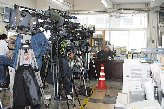 Jアラートの前に陣取る報道陣=10日正午ごろ、市役所