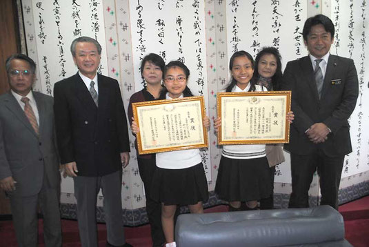 砂川さん(中央左)、迎里さん(同右)の家族と学校関係者が中山市長に受賞を報告した=29日午後、市役所