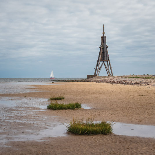 Der Leuchtturm Kugelbake in Cuxhaven an der Nordsee mit Segelboot und Wattenmeer