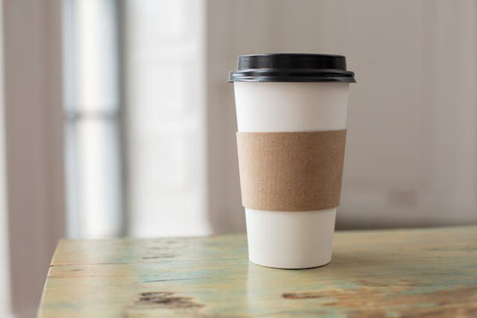 太陽の光が降り注ぐデスク。本と紅茶のティーカップ。観葉植物のグリーン。