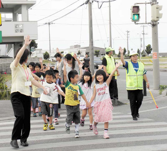 左右を確認し、手を挙げて横断歩道を渡る新入学児童=八島小付近交差点