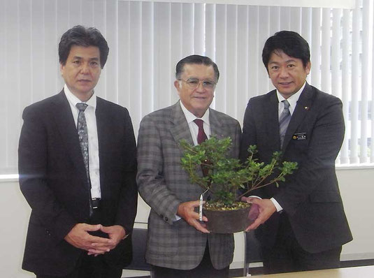 センカクツツジを中山市長に手渡す上原さん(中央)=自治会館(石垣市提供)