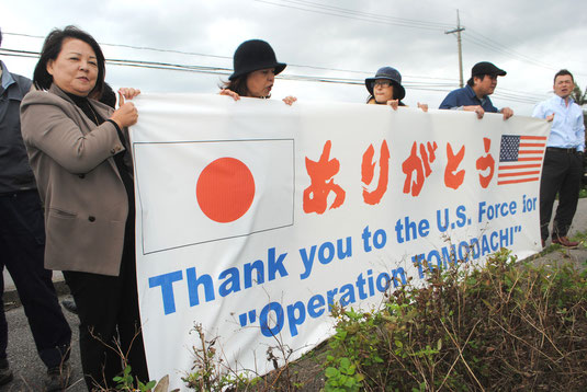 米軍機に向け、トモダチ作戦への感謝の横断幕を掲げる八重山防衛協会関係者ら(13日午後)
