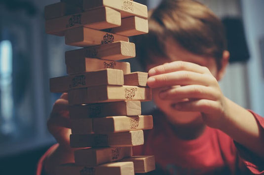 Confident young boy playing Jenga game.