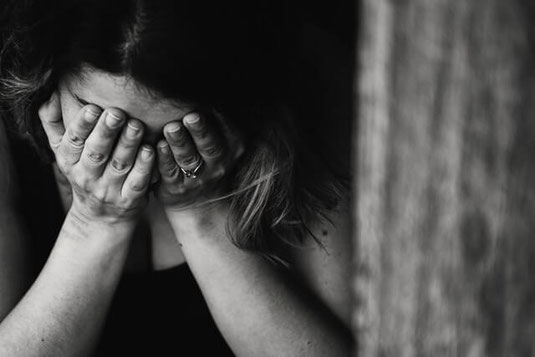 Anxious woman holding hands over face.