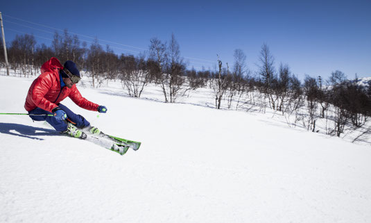 Man in red jackets skiing a carved turn