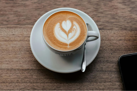 パラフィン紙に包まれたランチのパン。クリームパン、クロワッサン、チーズパン、カレーパン。コーヒーの入ったマグカップ。