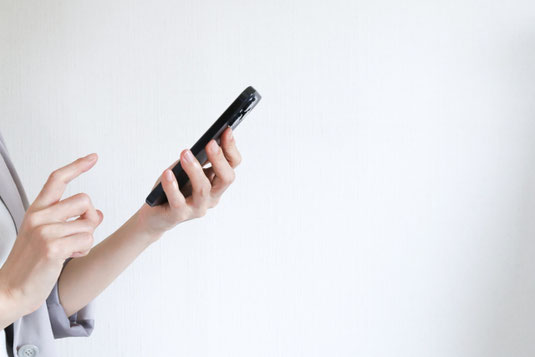 スマートフォンを操作するスーツ姿の女性の指先。