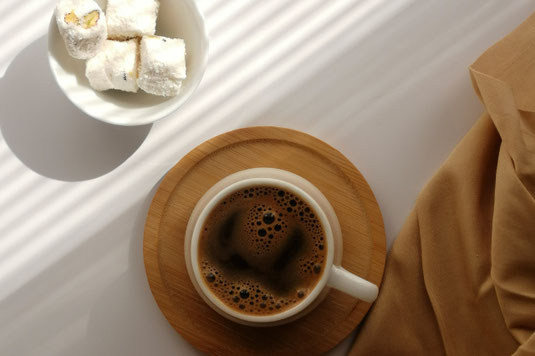デスクのうえに置かれた腕時計。コーヒーの入ったマグカップ。カスミソウが生けられた花びん。