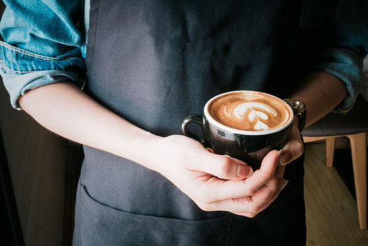 にぎわうカフェの店内。テーブルに置かれた白のマグカップ。