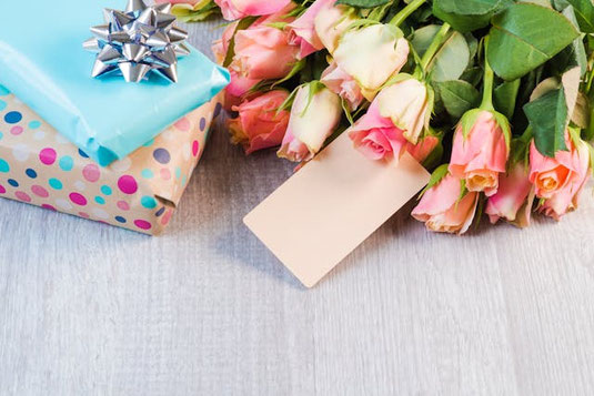 ラッピングされたプレゼントとバラの花束。メッセージカード。退職のはなむけ。