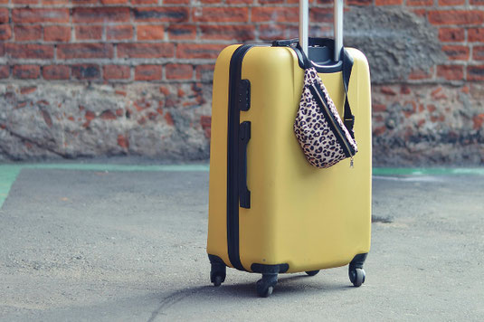 青空が広がる滑走路に置かれた真っ赤なキャリーケース。