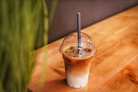 デスクに広げられたテイクアウトのハンバーガー、コーラ、ポテト。ポテトをつまむ指先。