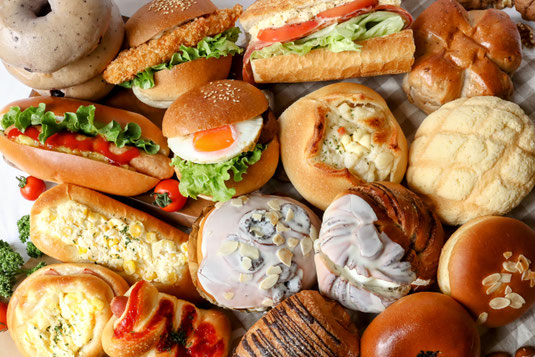 テーブルにずらりと並んだパン。バーガー、サンドイッチ、デニッシュ、メロンパン、クリームパン、あんぱん。