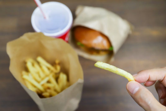 デスクに飾られたユーカリの小枝。マグカップに活けられている。傍らに氷の浮かんだアイスコーヒーのグラス。