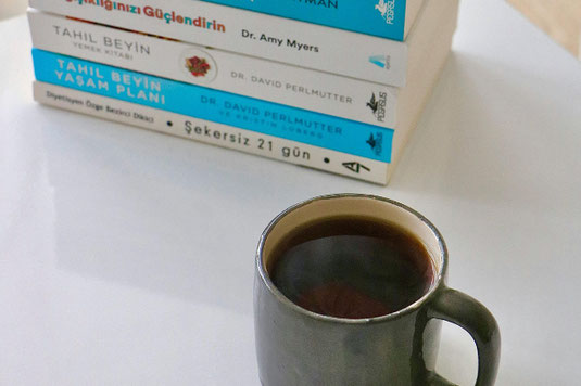 ページが開かれた洋書とドライフラワー、落ち葉、まつぼっくり、どんぐり。