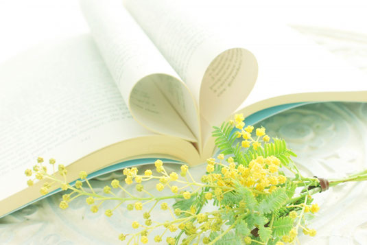 ページがハート形に折られた本とミモザの花。