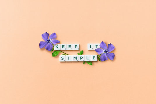 スミレの花とKEEP IT SINMPLEの文字列に並べられたアルファベットの積み木。