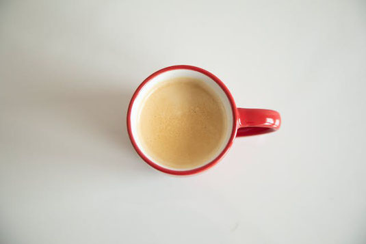 コーヒーの入った赤色のマグカップ。