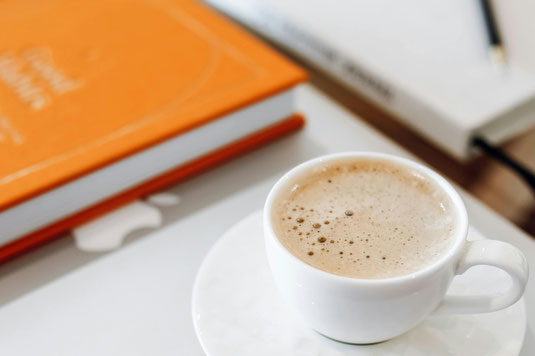 木目調のテーブルに置かれたテイクアウトコーヒー。コーヒー豆と麻袋。