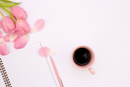 ピンクの芍薬の花。ページが開かれた書籍。コーヒーの入ったカップ&ソーサ。