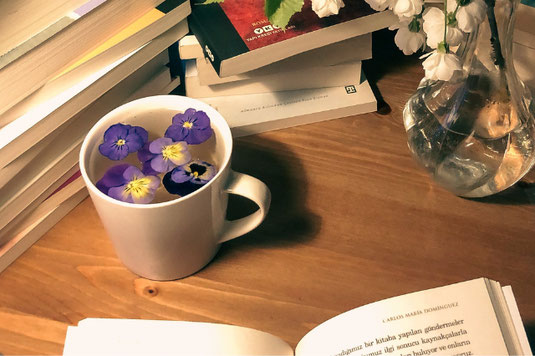 手帳をのぞき込む社員の手。紅茶の入ったカップ&ソーサ。はさみ。