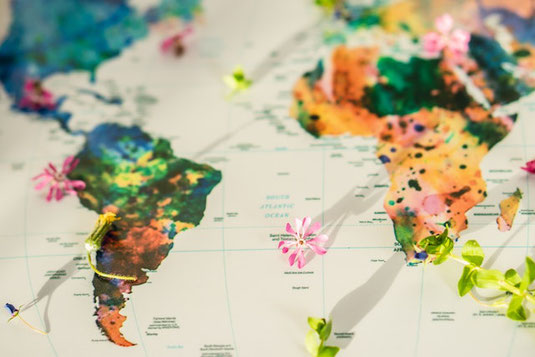 世界地図がペイントされた両掌を青空にかざしている。