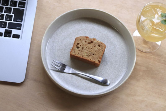 ノートパソコンの傍らにパウンドケーキのお皿とジュースのグラス。副業。