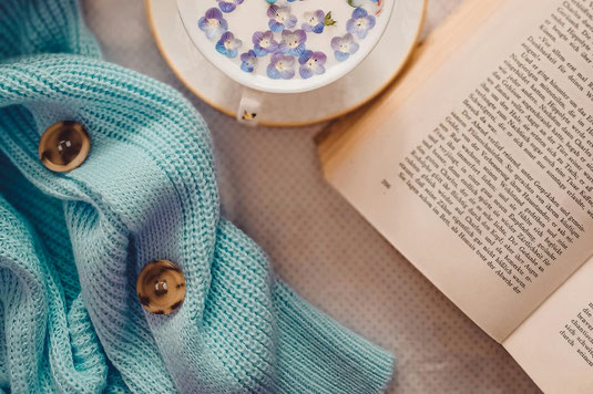 ページが開かれた洋書のうえに無造作にちりばめられた花びら。ピンクのカーネーションとユリの花。