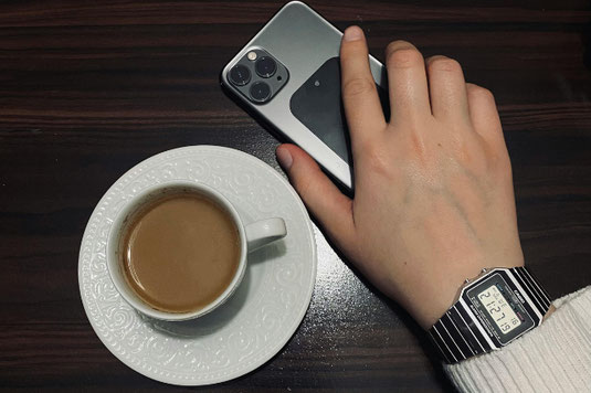 ノートパソコンとブラックコーヒーのマグ。リングノートの上に置かれたべっ甲フレームの眼鏡。