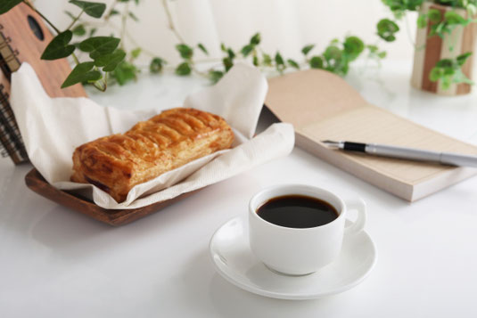 デスクにメモ帳と万年筆。コーヒーの入ったカップ&ソーサ。アップルパイののったトレイ。デスクの端に立てかけられたリングノート。