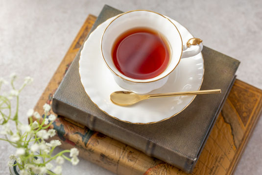 積まれたハードカバーの本のうえに紅茶のカップ＆ソーサ。