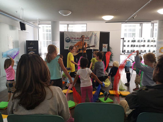 Kinder tanzen mit bunten Tüchern zu Gitarren-Live-Musik