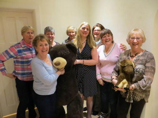 A group of Altos from the Wessex Chorus choir smiling with a giant teddy.