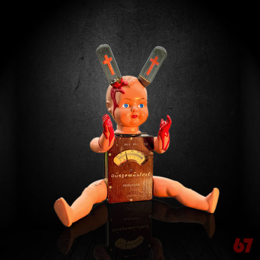 Messstrolch is an assemblage artwork with historical parts: Antique doll, old measuring device, neon glow bulbs 