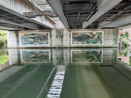 Unter einer Brücke an der Somme spiegeln sich Gemälde im Wasser des Flusses. 