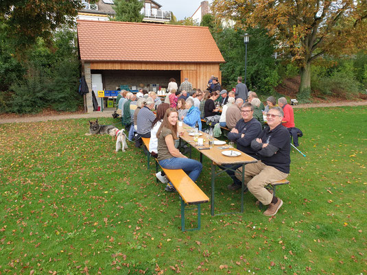 Teilnehmer der Wanderung sitzen gemeinsam bei Brotzeit und Musik.