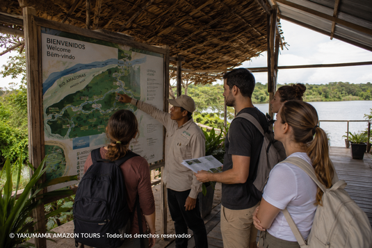 Guía amazónico explicando el itinerario de un tour a un grupo de viajeros en un albergue cerca de Iquitos antes de comenzar una expedición por la Amazonía peruana.