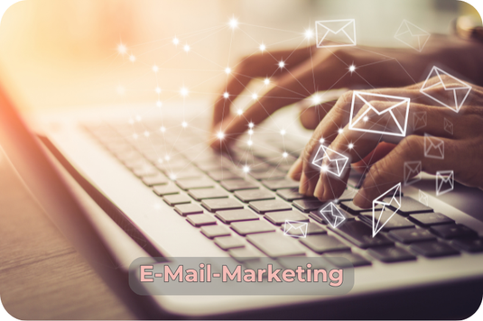 Hände tippen auf einer Laptop-Tastatur, darüber schweben stilisierte E-Mail-Symbole. Unten steht der Schriftzug „E-Mail-Marketing“.