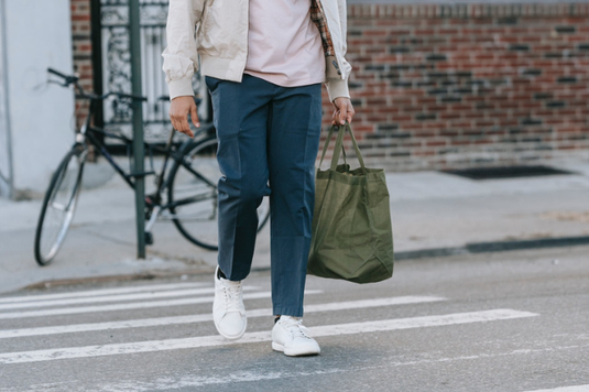 横断歩道を渡るトートバッグを手にしたビジネスカジュアルの装いの男性。朝の通勤。
